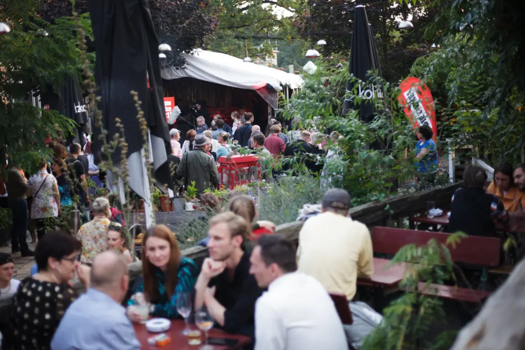 Das grüne Außengelände der Wahlparty der Partei "Die Linke". Im Vorder- und Hintergrund unterhalten sich Menschen.