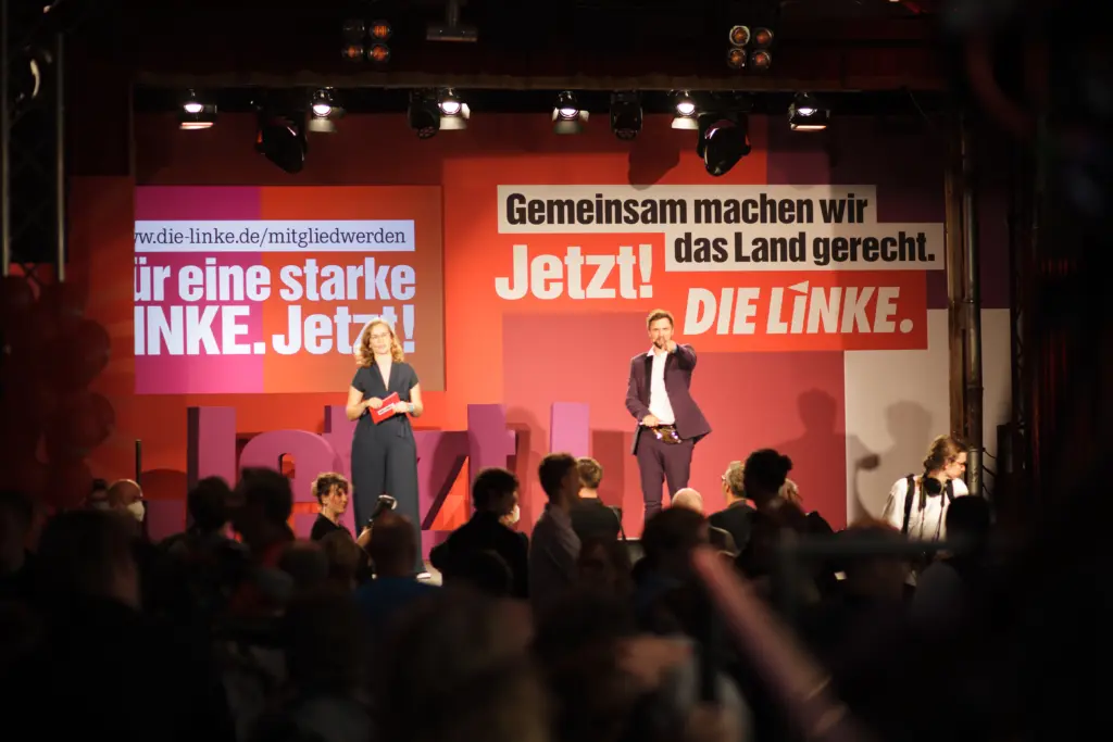 Die Moderator*innen der Wahlparty der Linken auf der Bühne.