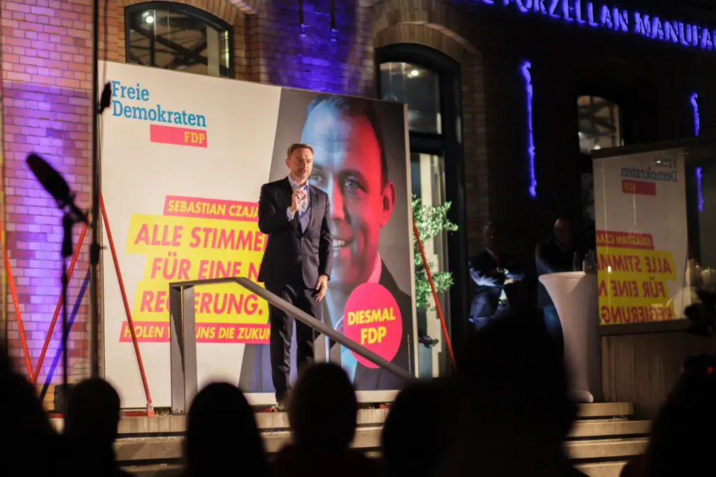 Christian Lindner steht auf der Bühne vor einem großen Wahlplakat und hält eine Rede.