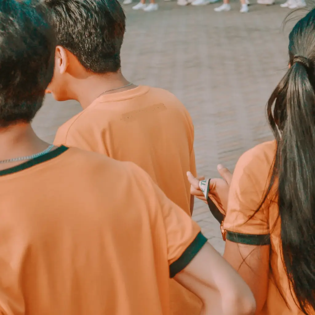 Drei Jugendliche in orangenen T-Shirts.