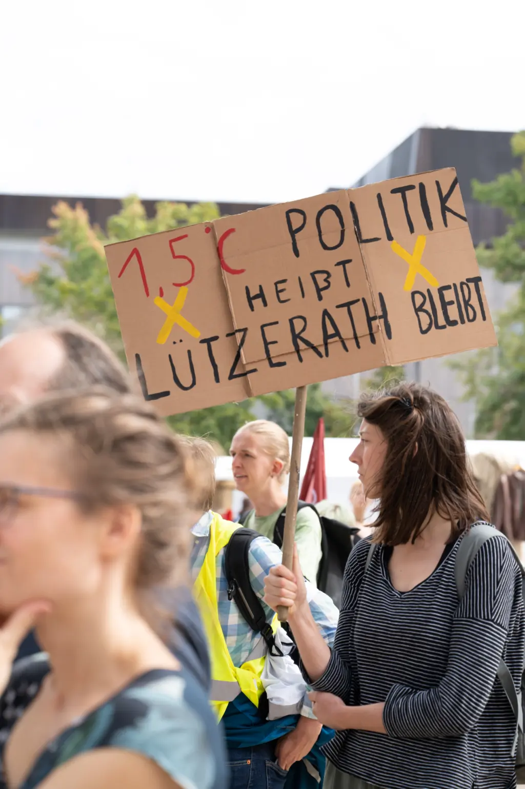 FridaysForFuture-Demonstrant*innen. Eine Demonstrantin hält ein Pappschild mit der Aufschrift: 1,5-Grad-Politik heißt Lützenrath bleibt.