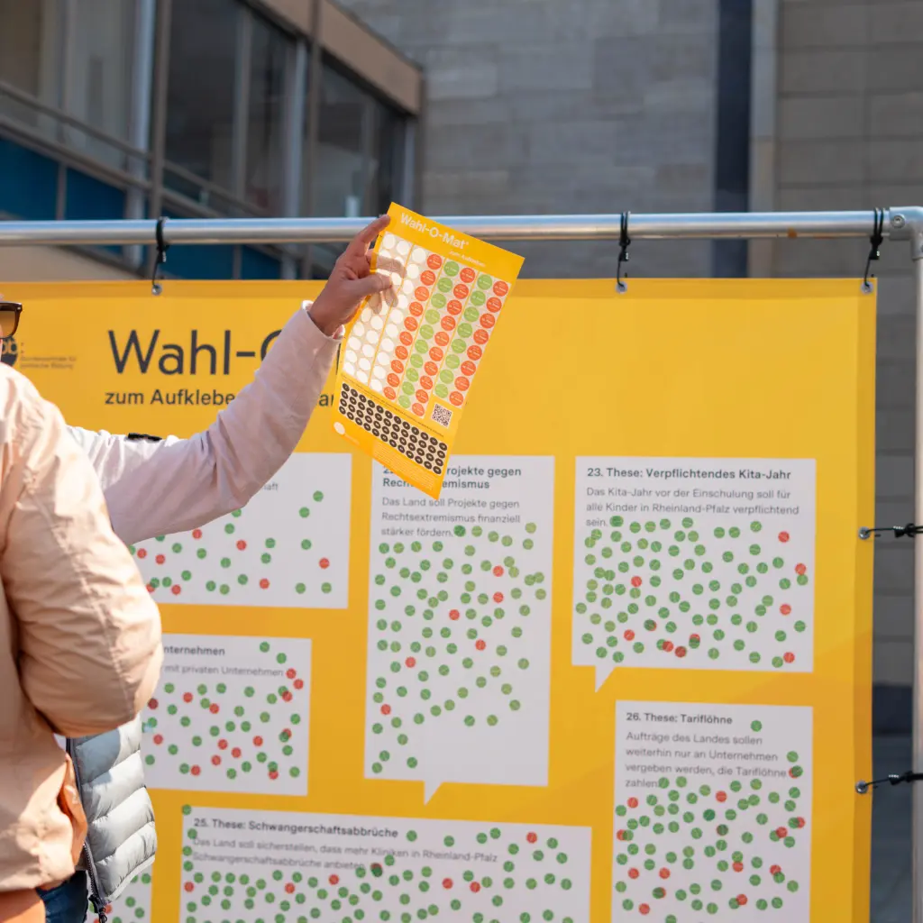 Menschen unterhalten sich beim Bestickern des analogen Wahlo-O-Mat.